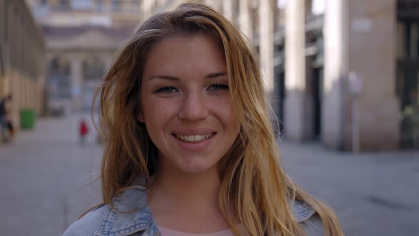 Close up portrait of cheerful attractive young Caucasian woman happy smiling face on street. Female people with joyful expression looking at camera outdoor. Blonde gen z girl posing natural for photo | Shutterstock HD Video #1111850557