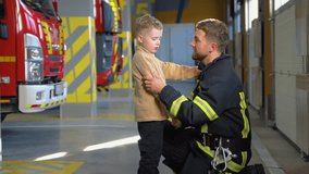 Firefighter and little boy at fire station. Fireman teaches a little boy fire safety regulations - Powered by Shutterstock - Get 15% off with code: PIKWIZARD15
