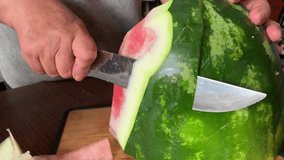 Video of hands cutting and peeling a watermelon. Food concept.