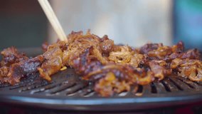 Japanese and Korean style barbeque meat grilled on grill pan. Cooking using chopsticks