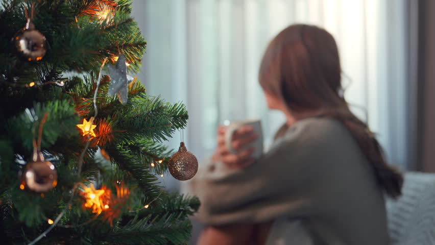 Alone beautiful charming asian woman drinking coffee on xmas Eve at living room with festive interior, Side view of young female with cup sitting by window at home at Christmas time | Shutterstock HD Video #1111856321