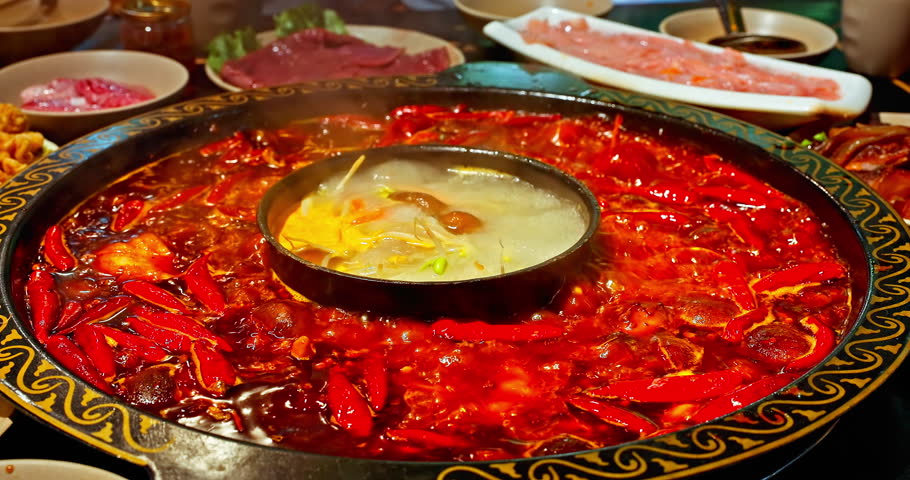 Chinese spicy hot pot cuisine. A layer of red chili pepper floats in the boiling hot pot base. Famous Chongqing Spicy Hot Pot, China. | Shutterstock HD Video #1111856371