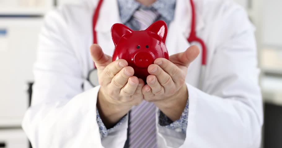 Young smiling male doctor holds piggy bank in hands. Medical insurance concept Royalty-Free Stock Footage #1111865307