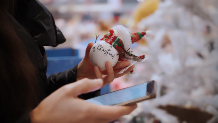 Use mobile phone. Christmas decorations. shopping. close-up. Customer typing in smartphone, while choosing gifts, festive accessories in a store, fair, supermarket or shopping mall in the run-up to | Shutterstock HD Video #1111867209