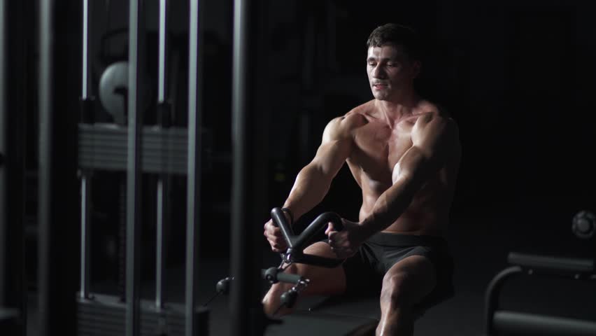 Athletic man in the Gym lifting blocks on rowing machine, hard training on block device and gym equipment, night training, cinematic light. | Shutterstock HD Video #1111867553