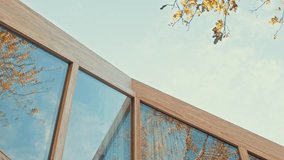 Autumn leaves frame a modern cabin's wooden and glass facade - Powered by Shutterstock - Get 15% off with code: PIKWIZARD15