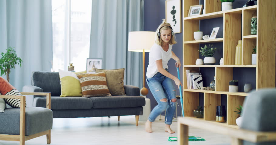 Cleaning, singing and a woman with headphones for music in a house for fun energy and housework. Young female person in her apartment home with happiness, dancing and joy to mop and clean floor | Shutterstock HD Video #1111873341