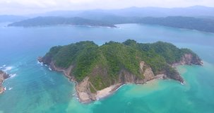 Aerial view of an island of the coast of Costa Rica surrounded by magical turquoise blue water on a sunny day in paradi