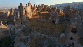 A captivating aerial stock video of the Cappadocia region in Turkey. Valleys with houses gracefully carved into the rocks unfold below, revealing its extraordinary charm. The unique rock formations