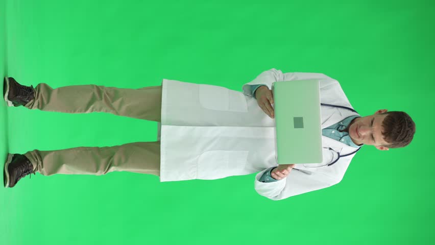 Male doctor on a green background. uses a laptop at full height | Shutterstock HD Video #1111878627