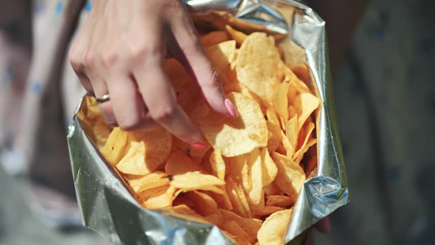 A girl eating chips on a summer afternoon. A pack of chips in close-up. | Shutterstock HD Video #1111882561