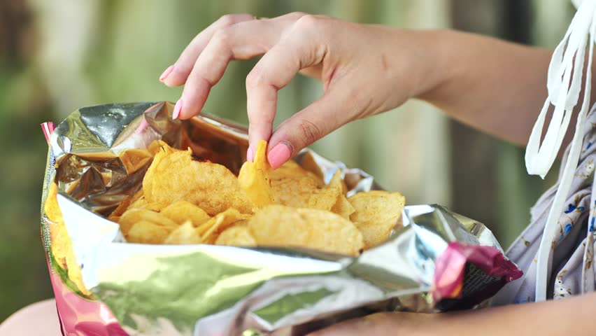 Girl eating chips on the street. Close-up of the hands. | Shutterstock HD Video #1111882563