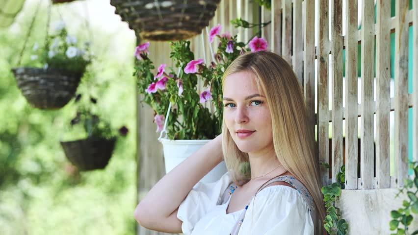 A girl of Slavic appearance poses at home with flowers. | Shutterstock HD Video #1111882565