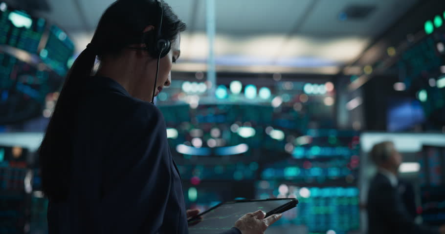 Young Asian Female Broker Working on Tablet Computer on Stock Exchange Floor. Traders Monitoring Real-Time Stocks, Commodities and Exchange Market Data. Professional Investment Agents in Office Royalty-Free Stock Footage #1111884161