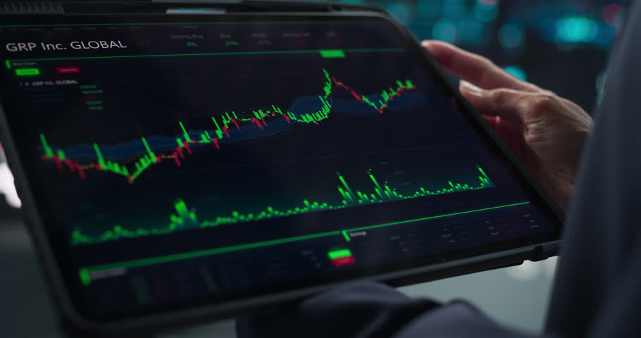 Close Up Footage of a Tablet Computer Monitor Screen with Real-Time Stocks, Commodities, Exchange Market Charts with Tickers on Display in a Financial Business Office