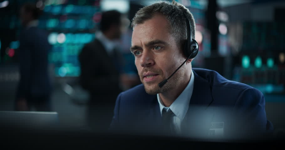 Handsome Adult Stock Exchange Trader Following a Live Auction, Communicating Buy and Sell Orders to Operator on the Other Side of the Call. Professional Investment Banker at Work. Slow Motion Footage Royalty-Free Stock Footage #1111884373