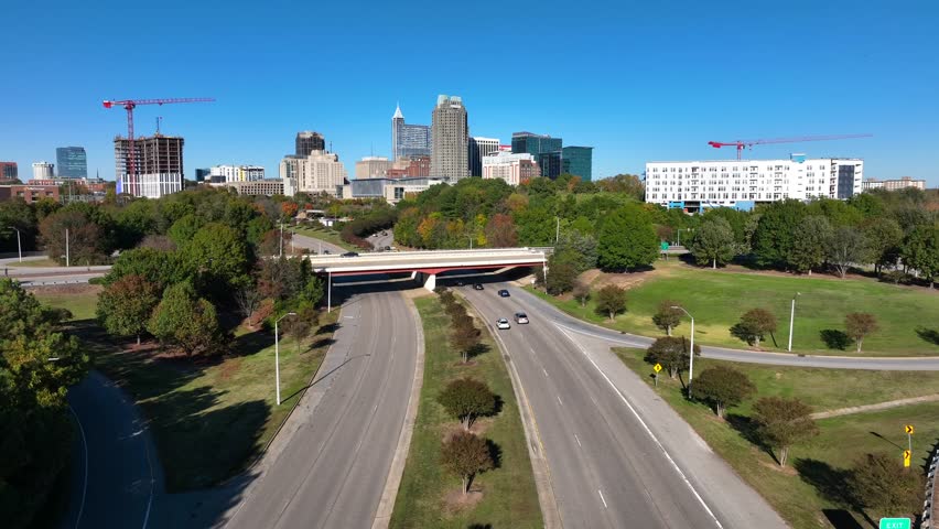 Highway traffic entering downtown Raleigh, North Carolina. Aerial rising shot revealing skyline.