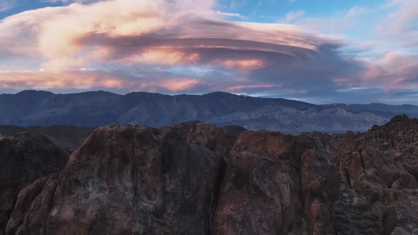 The most beutiful pink lenticular clouds and a lone bird flying through this rocky scene of Alabama Hills.