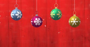 Animation of merry christmas text and christmas baubles on red background. Christmas, tradition and celebration concept digitally generated video.