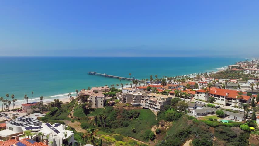 Overlooking Coastline And Long Wooden Pier Of San Clemente In Orange County, California. aerial sideways