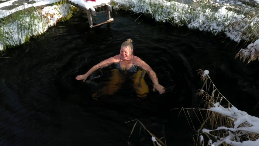 An elderly woman swims in the cool water of a garden pond. Hardening is her lifestyle. Adventure is ageless. | Shutterstock HD Video #1111894869