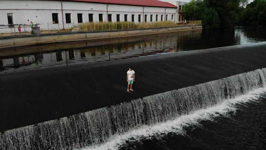 A drone view of a young guy standing on the dam of the Jizera River in the Czech Republic. Dam on the Jizera River in the Czech Republic. Village in Semilsky district of Liberec region