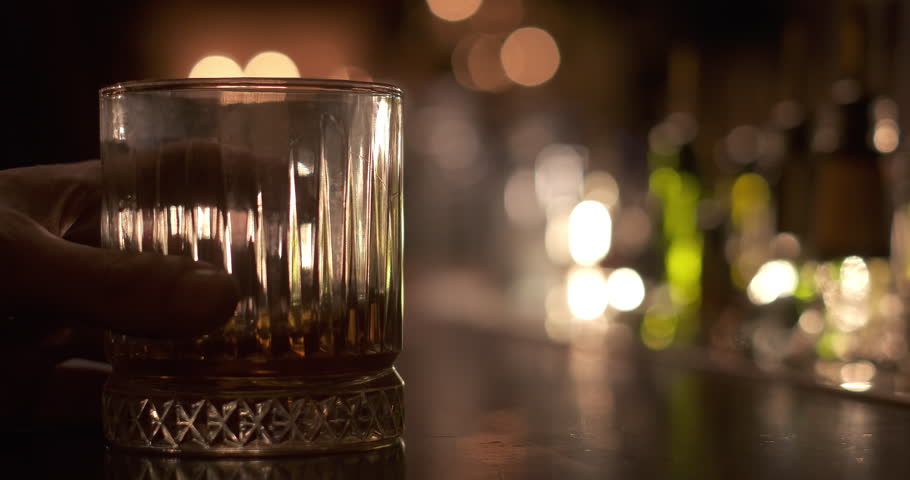 The bartender pushes a glass of whiskey to the customer. Enjoy fine alcoholic drinks beverage at the bar. Selective focus. Close up