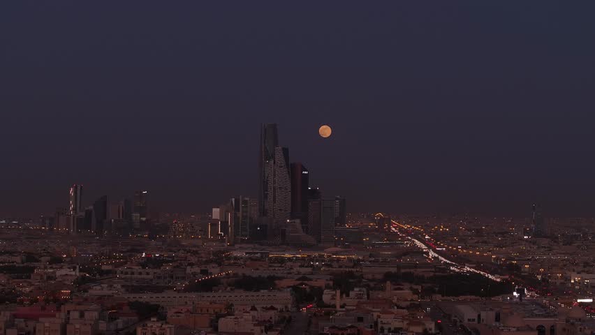 Drone shot of the full moon behind King Abdullah Financial District ( KAFD ) at dusk, Riyadh City, Saudi Arabia Royalty-Free Stock Footage #1111899989