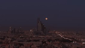 Drone shot of the full moon behind King Abdullah Financial District ( KAFD ) at dusk, Riyadh City, Saudi Arabia