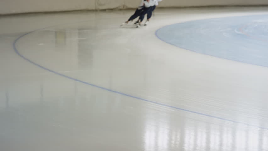 Pan slowmo shot of young polyethnic male group of athlete speed skaters sprinting in skating outfits in indoor ice rink | Shutterstock HD Video #1111900977