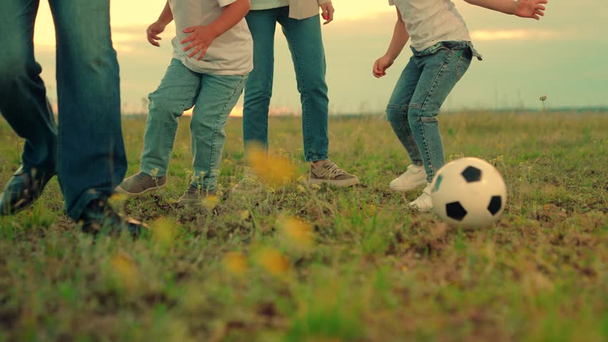 Happy family playing football. Family have fun playing soccer ball on lawn in park. Young family sport soccer team playing outdoors. Child kicks ball. Mom dad child play together, teamwork. Weekend | Shutterstock HD Video #1111902133