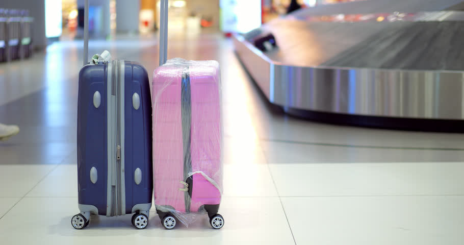 Pair of plastic cases left unclaimed at baggage carousel, women pass by. Selective focus with blurred background, low half composition. Clean bright interior of modern international airport arrivals | Shutterstock HD Video #1111906079