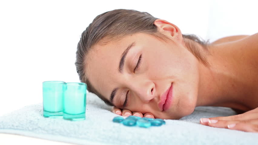 Portrait of pretty Caucasian brunette lying on massage table at the health spa in slow motion