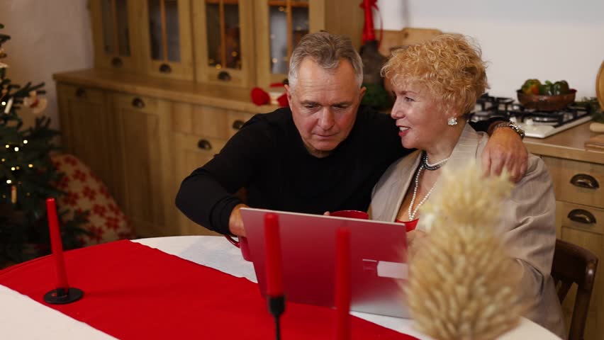 Senior Caucasian couple online shopping for presents for their grandchildren at home during christmas and the new year holidays.