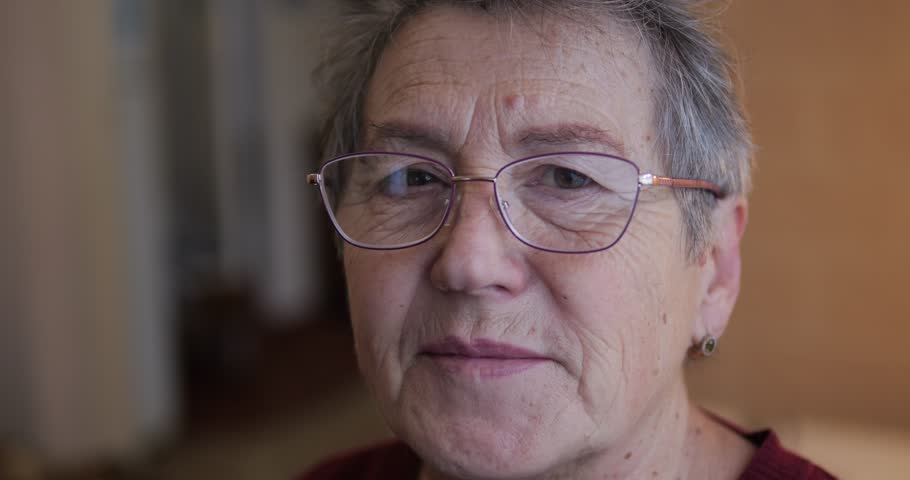 The face of an old woman in glasses. A woman with age-related wrinkles on her face smiles easily. | Shutterstock HD Video #1111917153