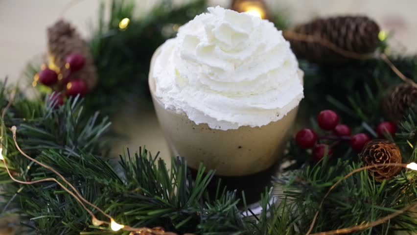 Cup of hot milk coffee with whipped cream festive seasonal drink with Xmas  sparkling bakground decoration. Christmas holiday season drinks cream cafe with twinkling lights.