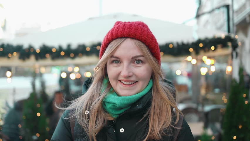 Beautiful winter portrait of young woman smiling girl with red lips, posing in street of european city. Winter fashion, Christmas holidays concept. 