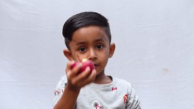 An Asian child is eating a red apple on an isolated white background. Fresh fruit-eating and enjoying concept 4k video. - Powered by Shutterstock - Get 15% off with code: PIKWIZARD15