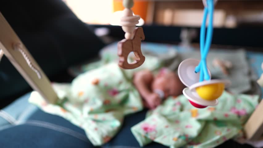 Small child sleeps in a cradle with toys hanging over him. happy family childhood dream concept. little newborn sleeps in soft bed toys over the crib close-up. light room in lifestyle the background | Shutterstock HD Video #1111923745