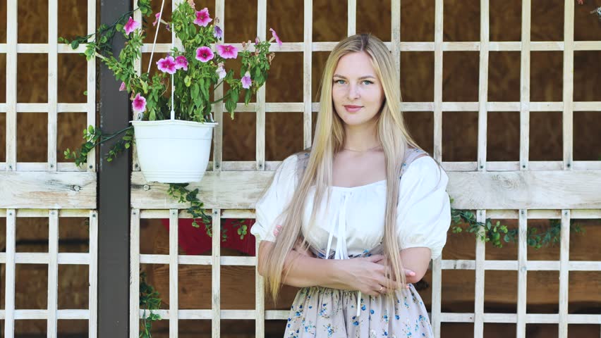 A girl of Slavic appearance poses at home with flowers.