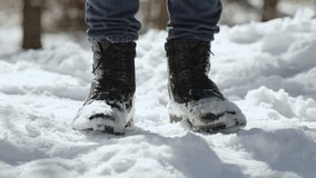 Man knocks his black boots together and shakes off snow in winter. Cleaning leather boots from stuck snow on frosty sunny morning. Dirty eco leather shoes after active trip. - Powered by Shutterstock - Get 15% off with code: PIKWIZARD15