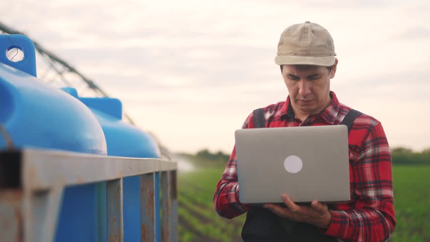 Irrigation agriculture. a male farmer works on a laptop in a field with corn. irrigation agriculture business concept. farmer scientist studying corn lifestyle. healthy natural foods concept | Shutterstock HD Video #1111926703