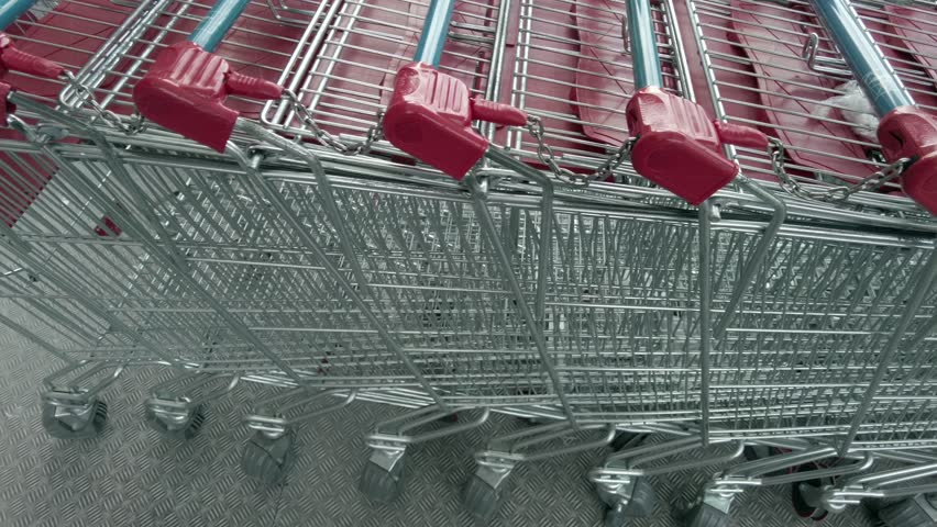 Row of shopping trolleys piled up outside a large food retailer - high cost of living and increase in the cost of food - empty shopping trolley, inflation | Shutterstock HD Video #1111927987