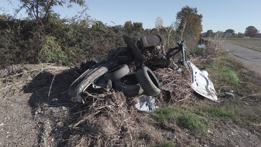 Car destroyed and demolished illegally in the countryside by the mafia underworld - environmental pollution and crime against nature and people's health - illegally disposing of dangerous waste | Shutterstock HD Video #1111928073