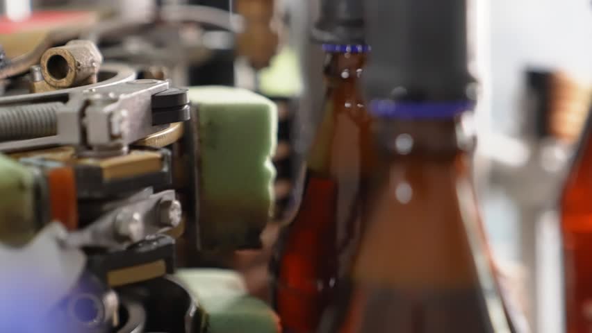 Craft beer production. Filling line, robotic process, caps for glass bottles. Line with bottles of beer. | Shutterstock HD Video #1111929349