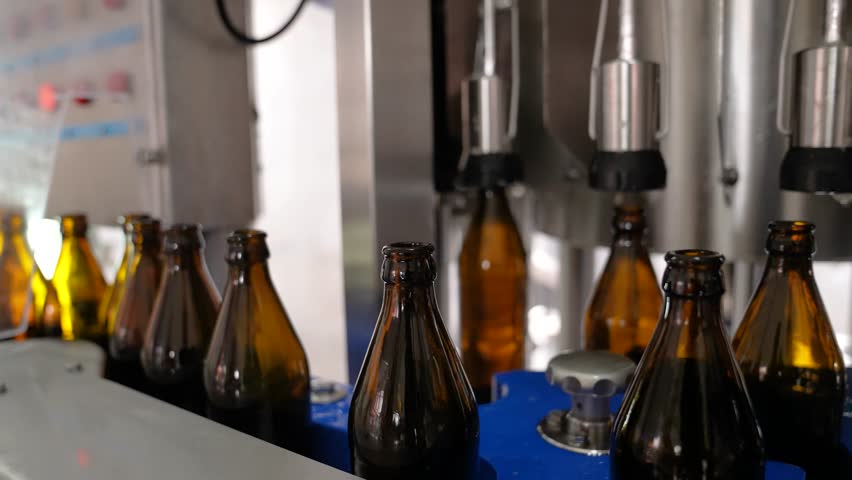 Craft beer production. Filling line, robotic process, caps for glass bottles. Line with bottles of beer. | Shutterstock HD Video #1111929351