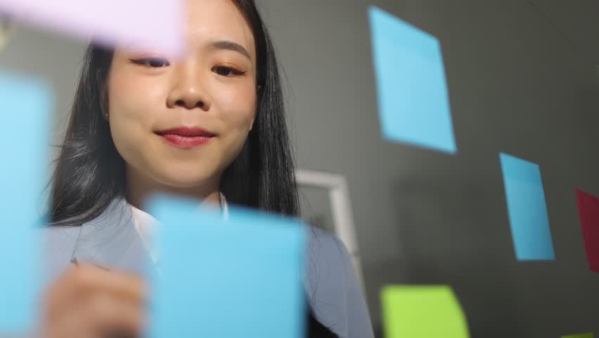 Creative young Asian woman thinking and planning a startup business with paper stickers on a transparent board. | Shutterstock HD Video #1111929967
