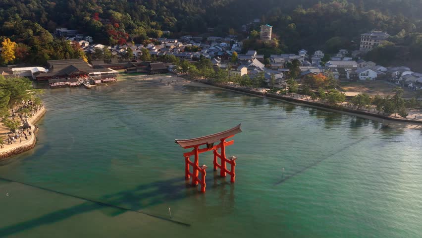Flying above an iconic torii gate in the sea on Miyajima island, Itsukushima Miyajima at Hiroshima Japan, tourism in Japanese Hiroshima. High quality 4k footage Royalty-Free Stock Footage #1111930191