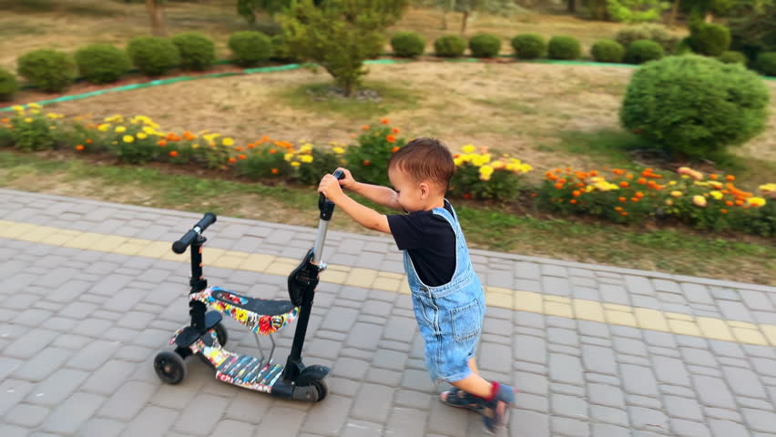 Active Caucasian toddler pushes his scooter bike. Energetic kid sits on the vehicle and rides it smiling happily . | Shutterstock HD Video #1111932111