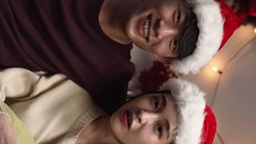 Vertical Screen: funny couple in sweater sit in comfort couch and face camera making online video call. front view young girl and boyfriend in santa hats smiling chatting on internet to lens - Powered by Shutterstock - Get 15% off with code: PIKWIZARD15